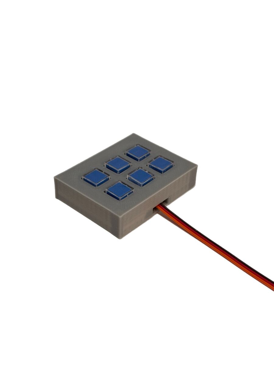 Graues Kunststoffgehäuse mit 6 blauen Tasten. Das Gehäuse enthält Kabel zur Verbindung mit anderen elektronischen Komponenten.